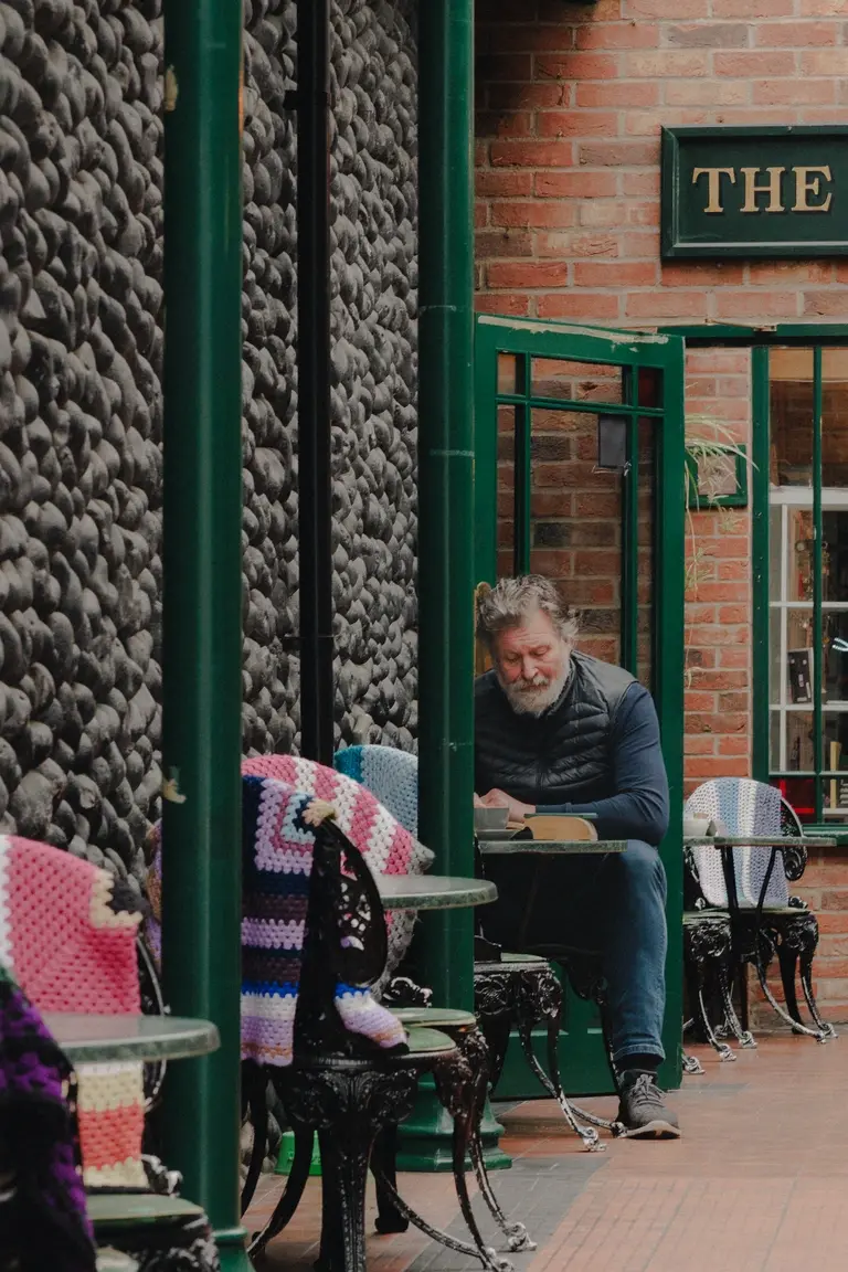 Man enjoying reading his book in cafe courtyard in Sheringham