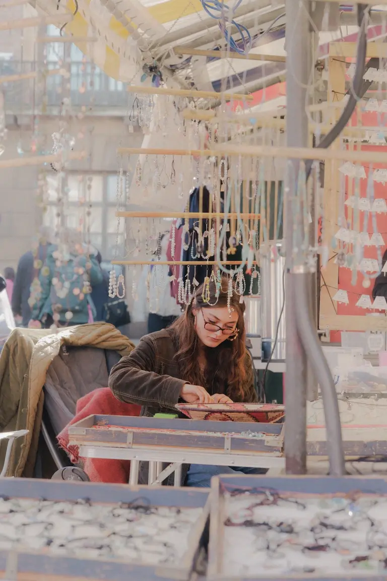 Woman working at market hand crafting beaded bracelets