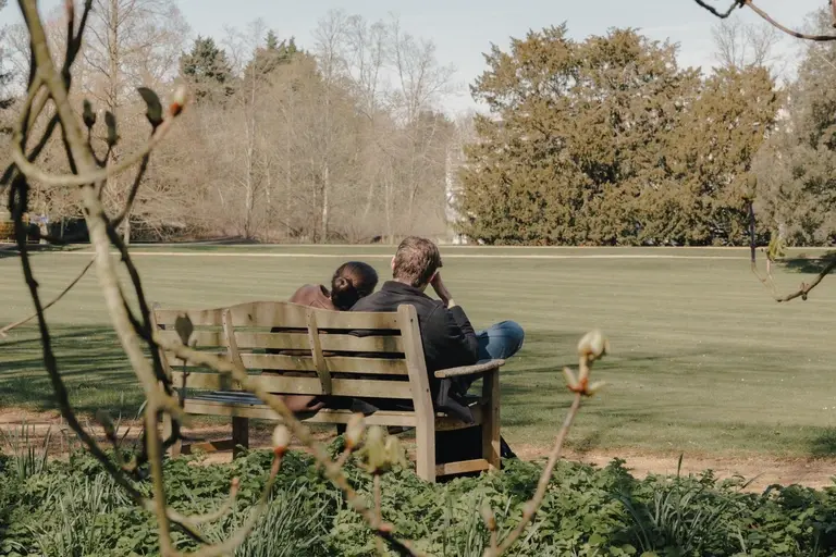 Couple sitting on bench overlooking St. John's College, Cambridge