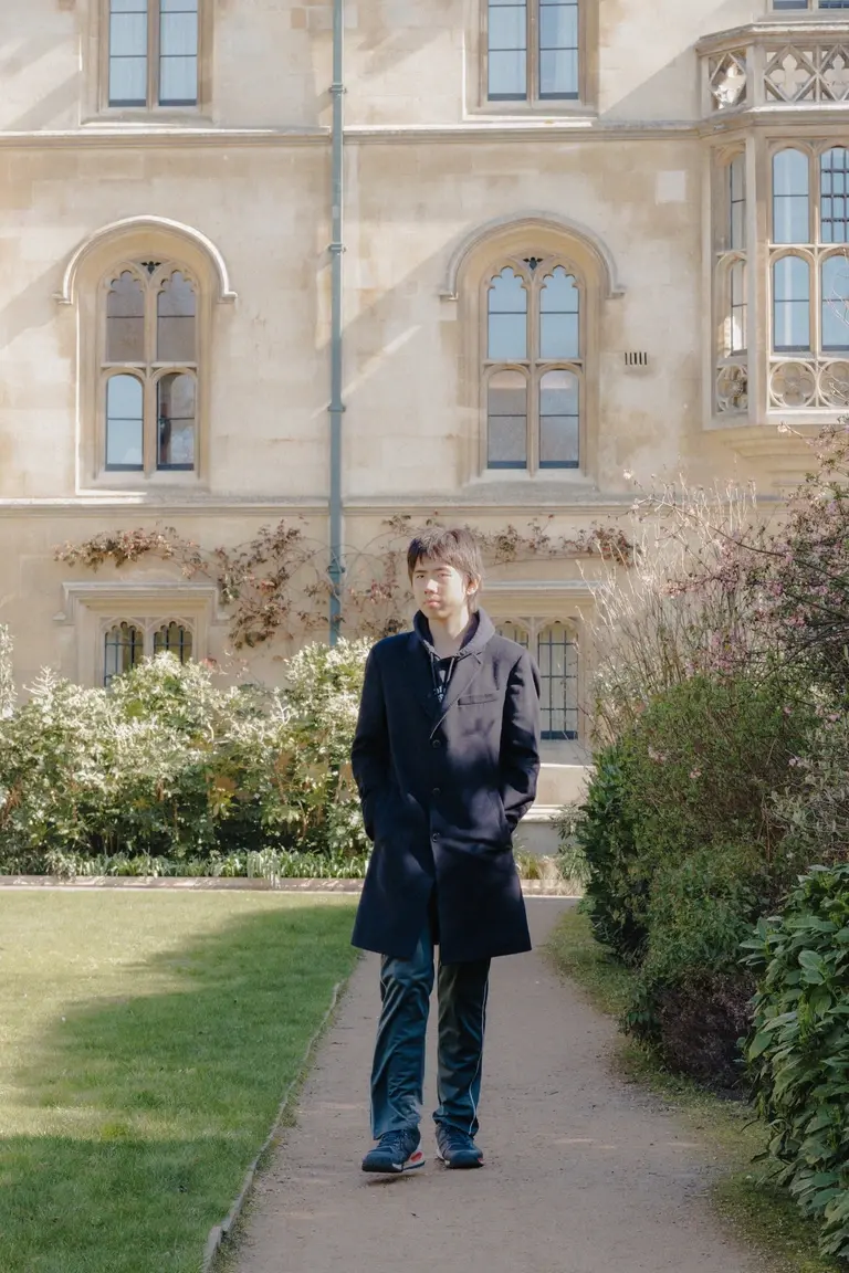 Young student walking down gardens in Cambridge college