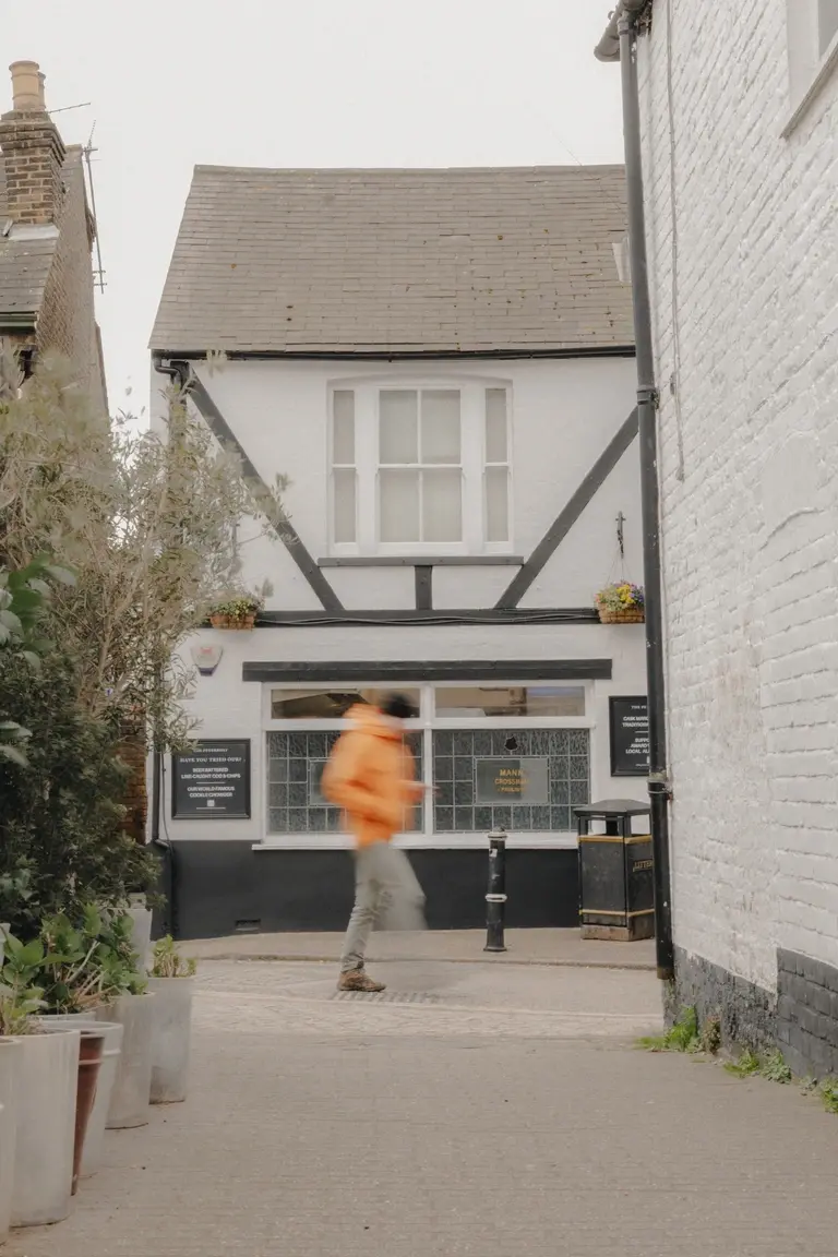 Man in Orange coat walking past Old Leigh streets