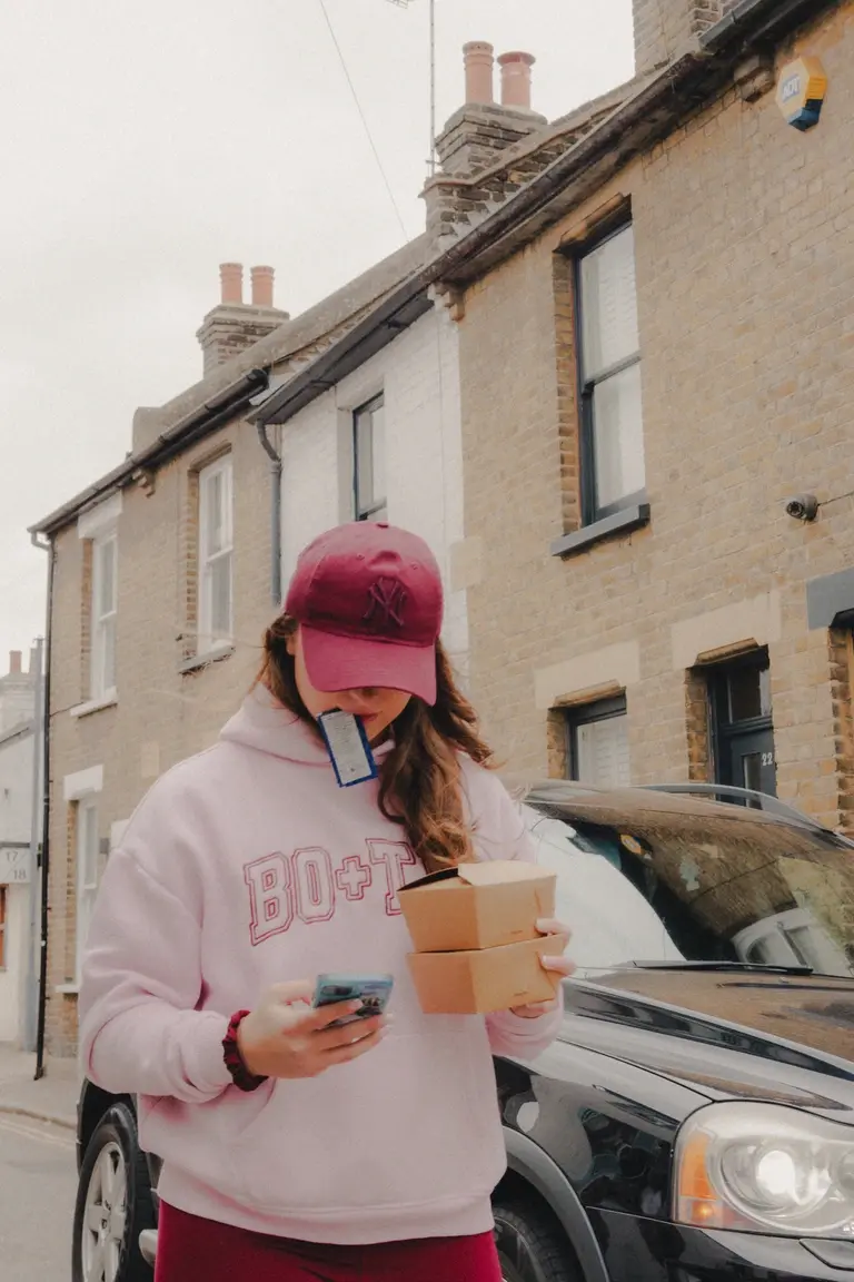 Woman multitasking with food and phone while walking down Old Leigh streets