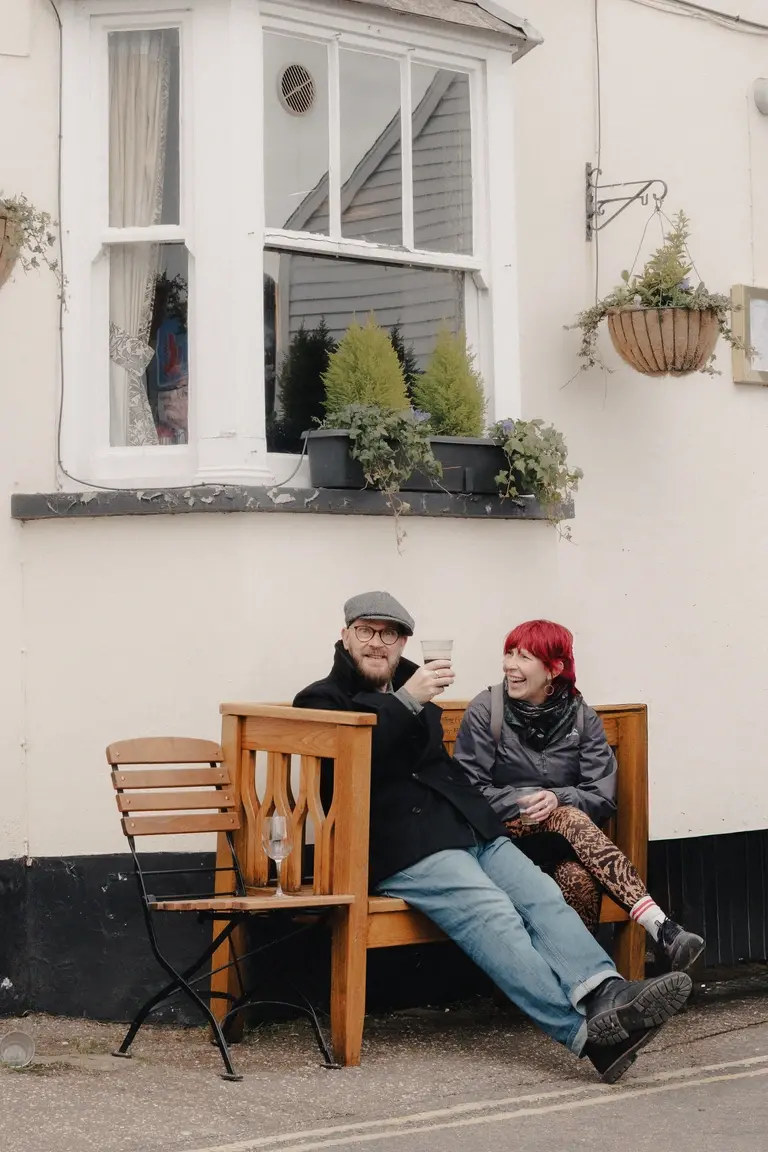 Couple staring and laughing from pub bench